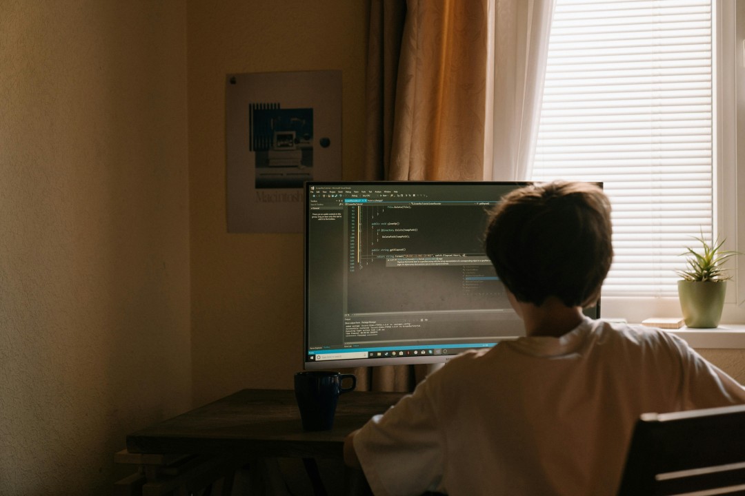 Developer coding a mobile application on Desktop with UI elements on screen